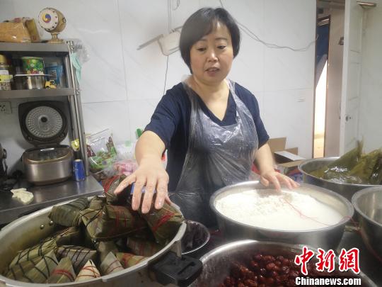 鄭春玲將兩張大粽葉窩成漏斗狀，填上糯米，放上兩粒紅棗，再加一片小粽葉，用棉線纏繞綁好，一個紅棗粽就成了，用時僅8秒?！「呖档?攝